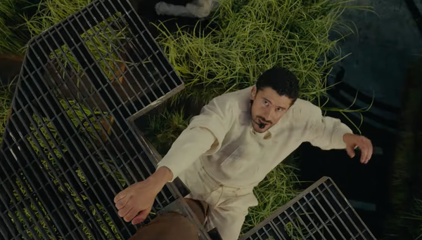 Bad Bunnty is a latino man in a white workout suit, climbing a prop powerline during the Super Bowl Half-Time Show.